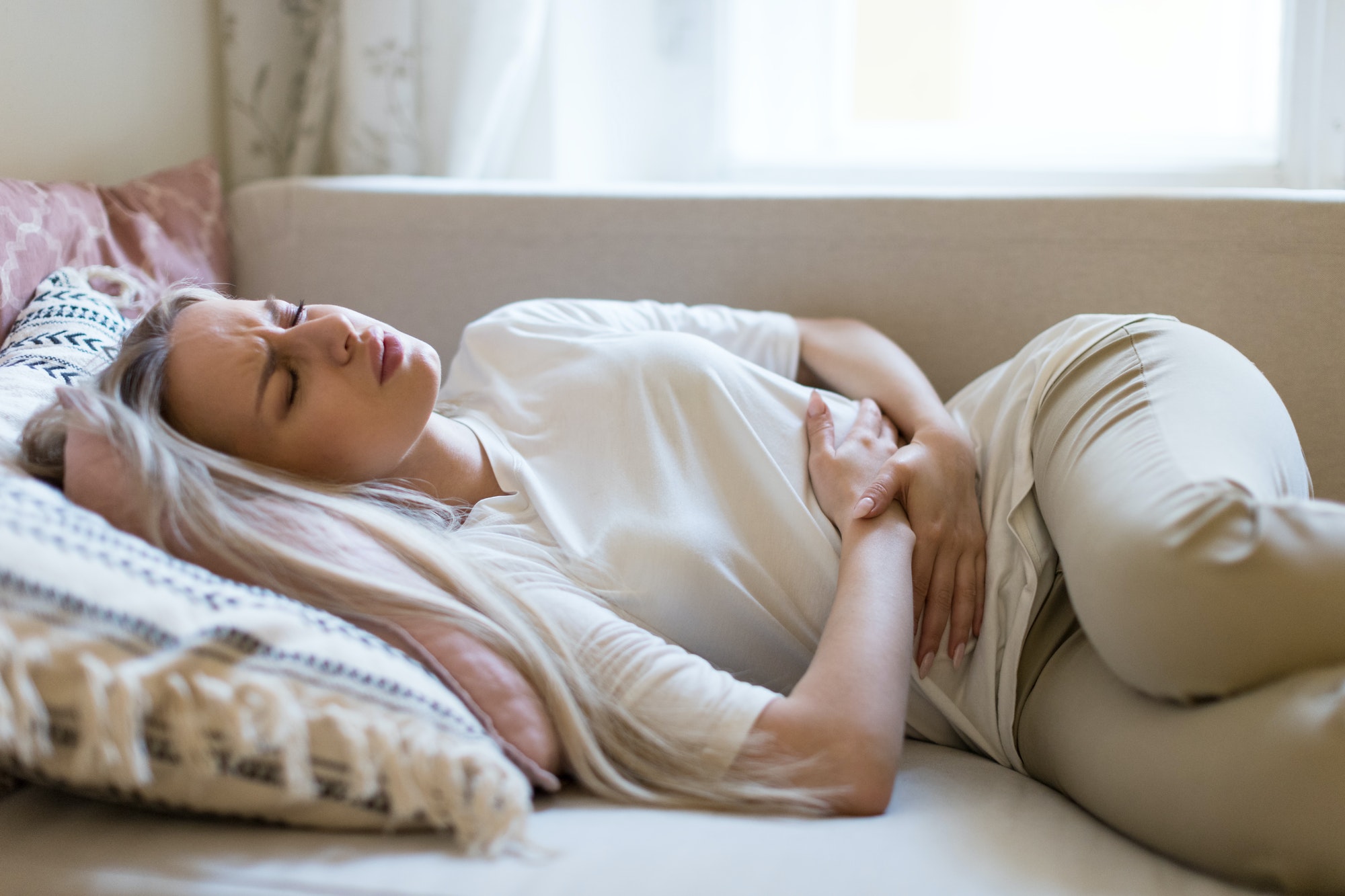 girl suffering from stomach pain feeling abdominal pain or cramps, lying on sofa.Period menstruation